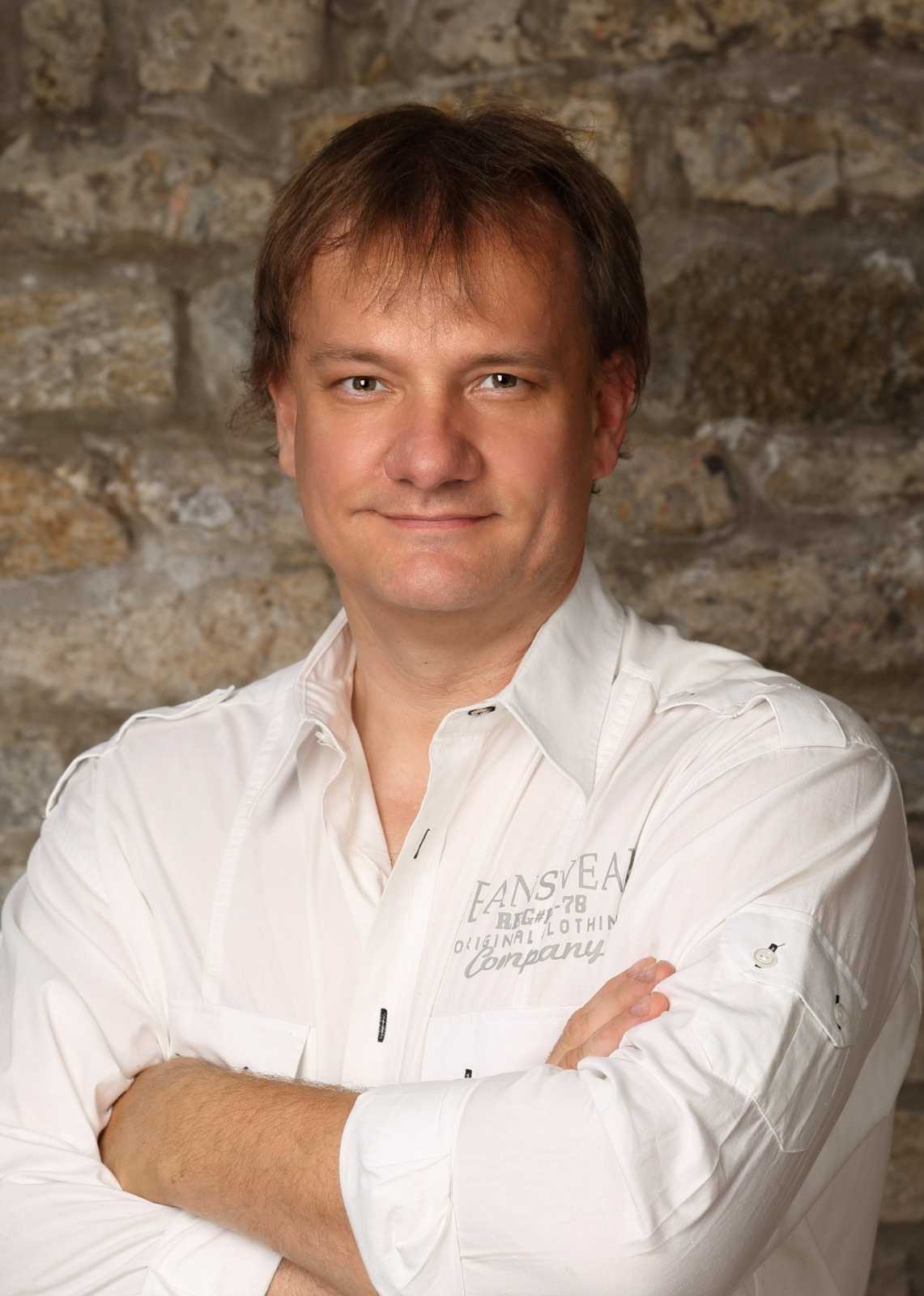 Portrait eines Mitarbeiters vor Steinwand, weißes Hemd – Ansprechpartner für Entrümpelung und Haushalts-/Firmenauflösung in Würzburg.