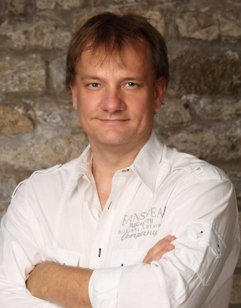 Portrait eines Mitarbeiters vor Steinwand, weißes Hemd – Ansprechpartner für Entrümpelung und Haushalts-/Firmenauflösung in Würzburg.